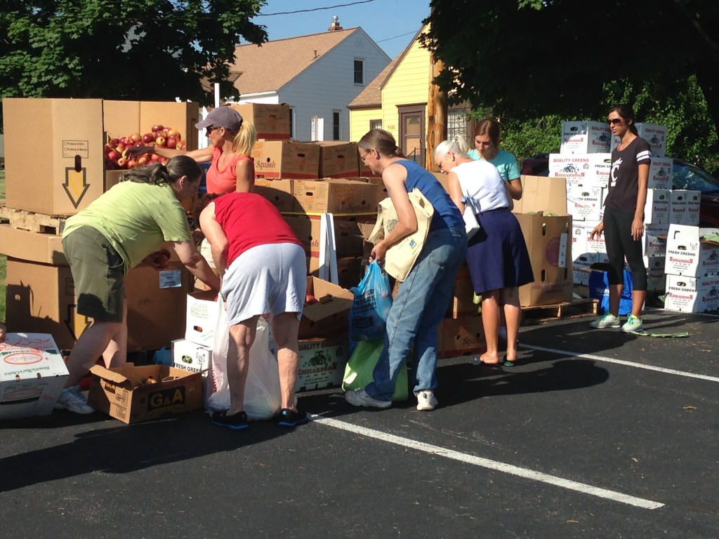 Volunteers work alongside a line of palettes stacked with boxes of produce and other groceries.