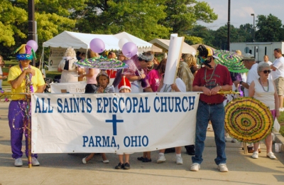 People in a parade holding a banner that reads "All Saints Episcopal Church, Parma, Ohio"