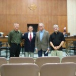 Four men stand and pose at the front of Parma City Hall chambers.